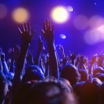 A crowd of people on the dancefloor with hands raised and disco
